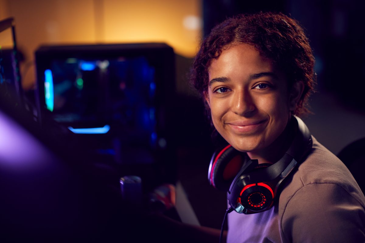 Portrait Of Teenage Girl With Headset Gaming At Home Using Dual